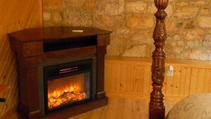 Un muro de piedra, un banco de madera y una chimenea con fuego encendido.