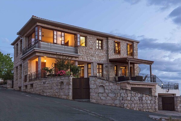 A two-story stone building with balconies, large windows, and a gated entrance.