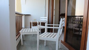 A balcony with two white chairs and a small table. - Beach Front Apartment. (Diani Beach)