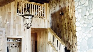 A wooden staircase with a stone wall on the right, leading to an upper level.
