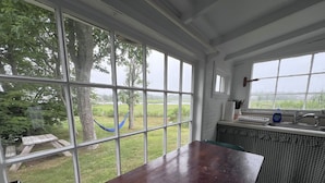 Une cuisine dotée de grandes fenêtres, d’une table en bois et offrant une vue sur un espace verdoyant avec des arbres.