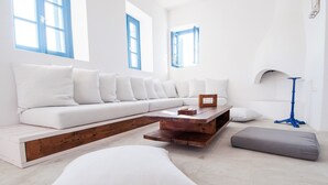 A modern living room with a white sofa, wooden coffee table, and a grey pouf. - Ocean View house with swimming pool ISLA summer homes (Paros)