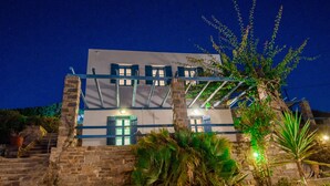 A building with a stone facade, multiple windows, and a staircase leading to the entrance. - Ocean View house with swimming pool ISLA summer homes (Paros)