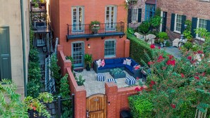A courtyard with a brick building, a wooden gate, and a seating area with cushions. - Private Heated Pool | 5*Clean | Flex Cancelation (Savannah)