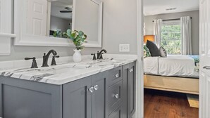 A modern bathroom with a large mirror, two sinks, and a vanity with drawers. - Private Heated Pool | 5*Clean | Flex Cancelation (Savannah)