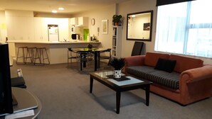 A modern living room with a sofa, coffee table, and a dining area with chairs and a table.
