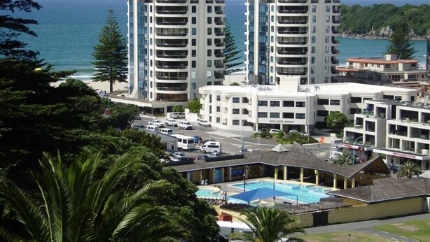 A coastal hotel with multiple high-rise buildings, a swimming pool, and a view of the ocean.