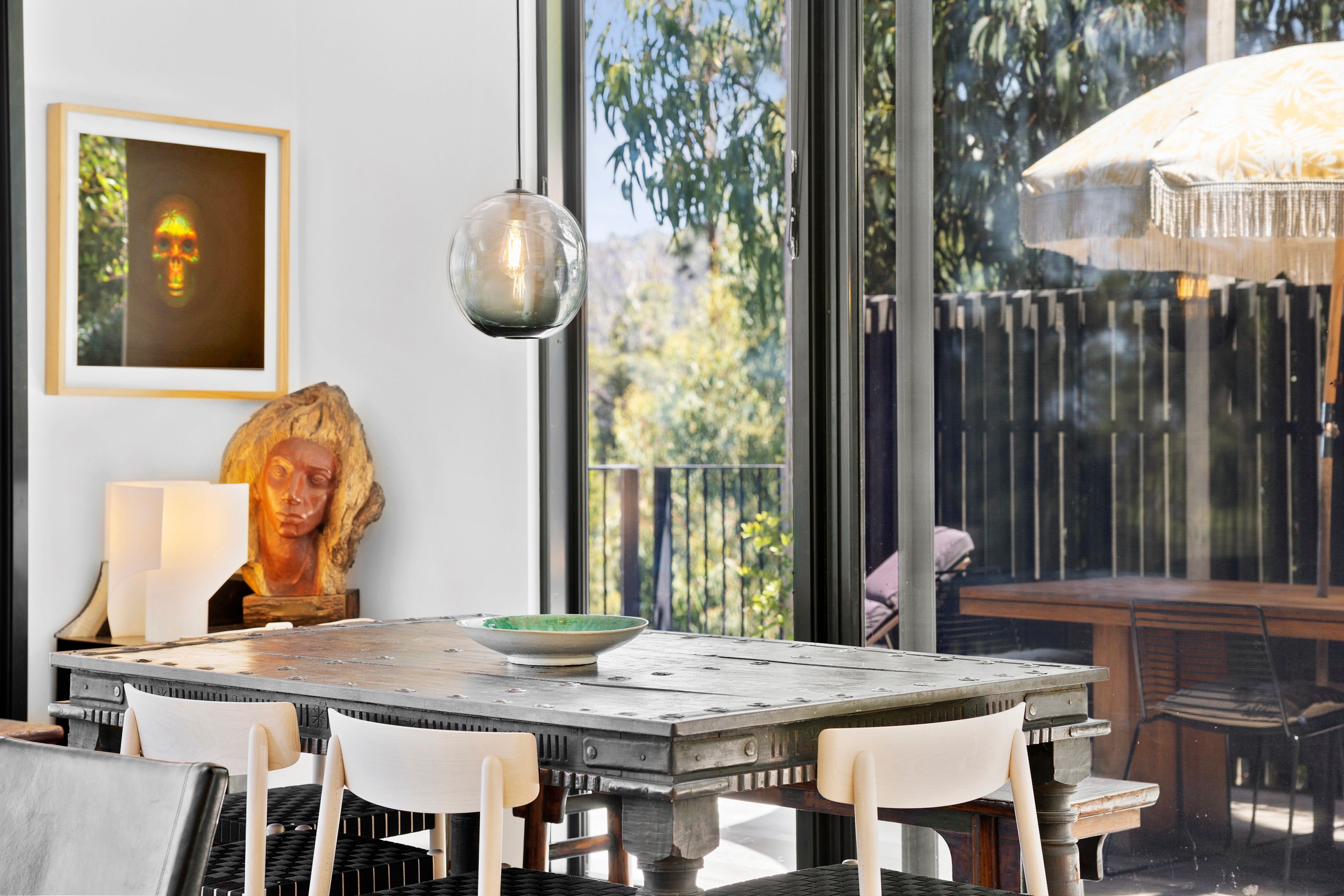 A dining area with a table, chairs, a hanging light fixture, and a view of the outdoors.