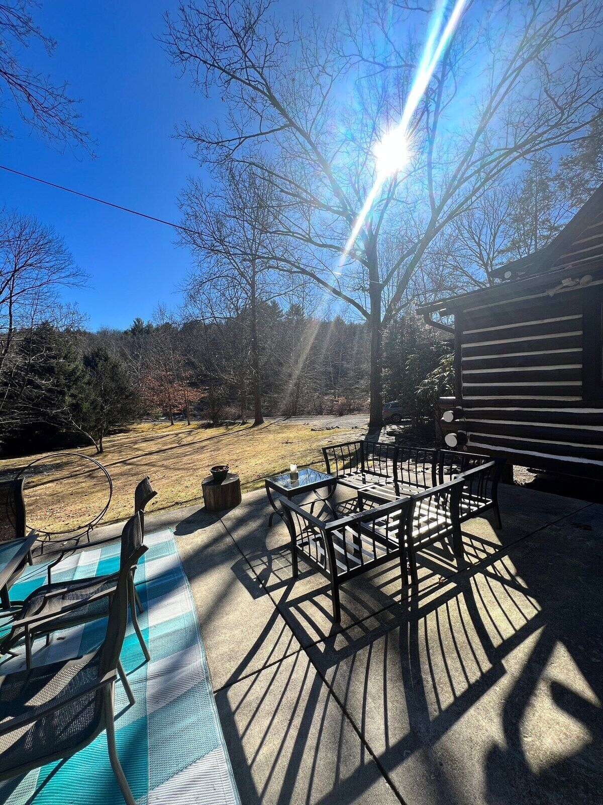 A patio with outdoor furniture, a wooden deck, and a view of the surrounding trees and sky.
