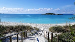 A sandy beach with a wooden staircase leading down to the water, a clear blue sky, and a small island in the distance. - Panoramic ocean view luxury villa with pool, few minutes walk to Palm Bay Beach (Georgetown)