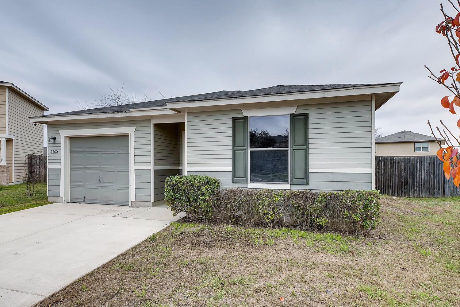 A single-story house with a garage, a small front yard, and a wooden fence in the background.