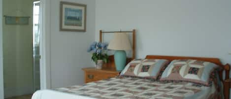Un dormitorio con cama, una mesita de noche con lámpara y un cuadro en la pared.