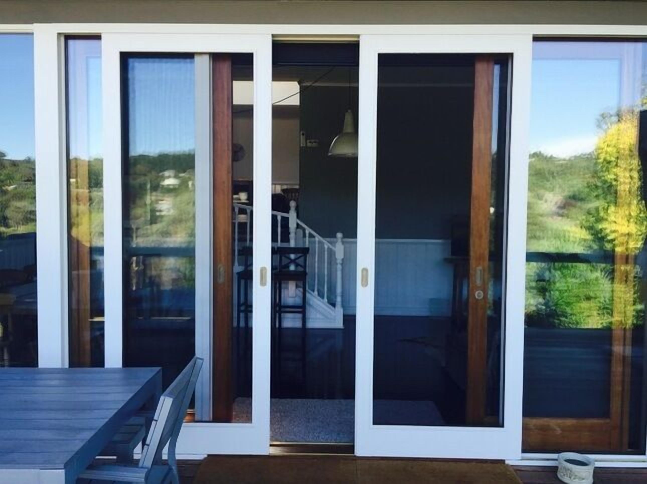 A modern home with large sliding glass doors leading to a covered outdoor area.