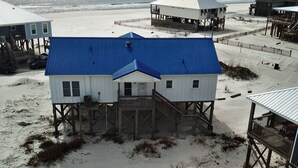 Il s’agit d’une propriété située en bord de mer, comprenant plusieurs bâtiments, dont une maison principale avec un toit bleu et une construction plus petite avec un toit blanc.