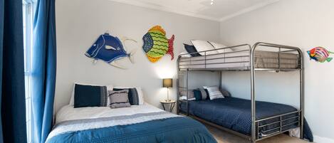 Une chambre avec un lit superposé, un lit simple et des décorations murales représentant des poissons.