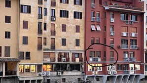 Un immeuble à plusieurs étages doté de balcons, d’un mur en pierre et d’une rivière au premier plan.