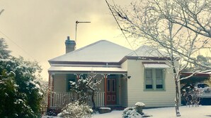 A house with a snow-covered roof, a chimney, and a porch. - Grevillea Cottage - Family and Group Getaways (Katoomba)