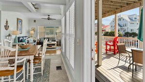 A covered porch with a dining area, a ceiling fan, and a view of neighboring houses. - CottageVacations4u "MEANT 2B" -pool club- ocean view-200 FT to beach. DOG FRIENDLY. (Ocean Isle Beach)