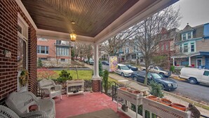 Eine überdachte Veranda mit Korbmöbeln, einer Backsteinmauer und Blick auf die Straße.