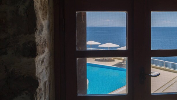 Puerta con vista a una piscina y sombrillas.