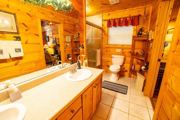 A wooden cabin bathroom with a sink, toilet, and shower.