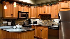 A kitchen with wooden cabinets, a microwave, a stove, and a refrigerator.