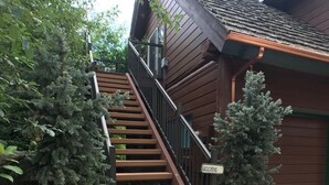 Un escalier en bois mène à un bâtiment sur lequel est affiché un panneau « Bienvenue », le tout étant entouré de verdure.