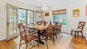 A dining room with a large wooden table, wicker chairs, and a chandelier.