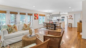 A spacious living area with a white sofa, wicker chairs, and a dining table.
