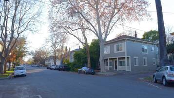A residential street with two-story houses, parked cars, and leafless trees.