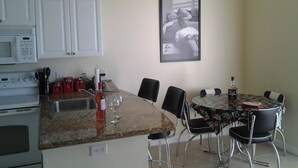 A kitchen with white cabinets, a microwave, and a dining area with a table and chairs. - Waterfront condo with private balcony. Sun All Day! (St. Petersburg)