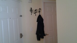 A room with two white doors, one with a metal handle and the other with a keyhole. A black coat hangs on a metal hanger on the wall. - Waterfront condo with private balcony. Sun All Day! (St. Petersburg)