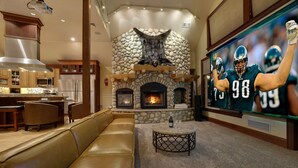 A modern living room with a stone fireplace, a large flat-screen TV, and a leather sofa. - Ski-In/Out, 2 Game Theaters, Hibachi Grill, 2 Masters, Hot Tub & Slope Views (Lackawaxen)