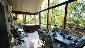 A covered outdoor dining area with a table set for four, surrounded by chairs, and a hot tub in the background. - Ski-In/Out, 2 Game Theaters, Hibachi Grill, 2 Masters, Hot Tub & Slope Views (Lackawaxen)