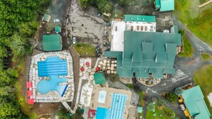 An aerial view of a resort with multiple swimming pools, a large building with a green roof, and a parking area. - Ski-In/Out, 2 Game Theaters, Hibachi Grill, 2 Masters, Hot Tub & Slope Views (Lackawaxen)