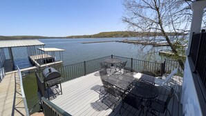 A deck with outdoor furniture overlooking a lake, dock, and distant hills. - Executive Getaway close to all the action with Private 2 slip dock  (Sunrise Beach)