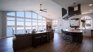 A spacious kitchen with large windows, a dining area with a view of the water, and a modern ceiling fan. - Executive Getaway close to all the action with Private 2 slip dock  (Sunrise Beach)