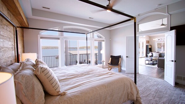 Un dormitorio con una cama grande, una silla y vistas a un balcón con barandilla.