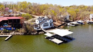 A lakeside property with a dock, a white house, and a restaurant with outdoor seating. - Executive Getaway close to all the action with Private 2 slip dock  (Sunrise Beach)