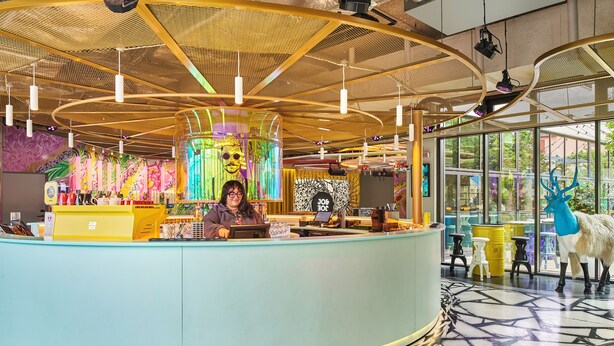 A brightly lit reception area with a curved counter, a large window, and a decorative deer statue. - JO&JOE Paris - Gentilly Hotel - Hostel (Gentilly)