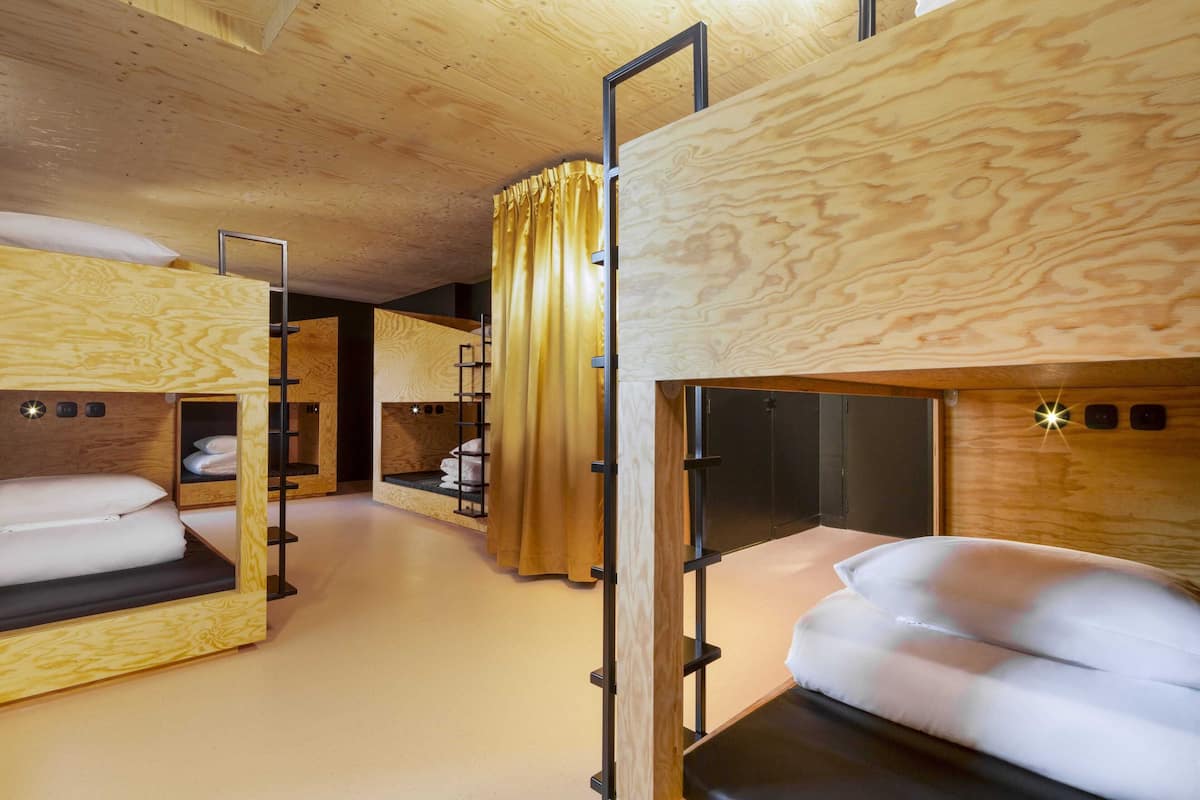 Quarto com beliches, paredes de madeira e cortina.