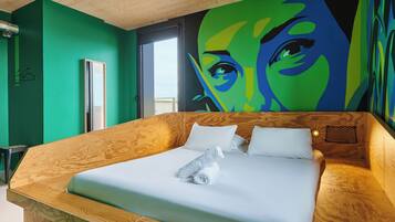 A modern bedroom with a wooden headboard, a large bed with white linens, a green wall, and a large abstract painting.
