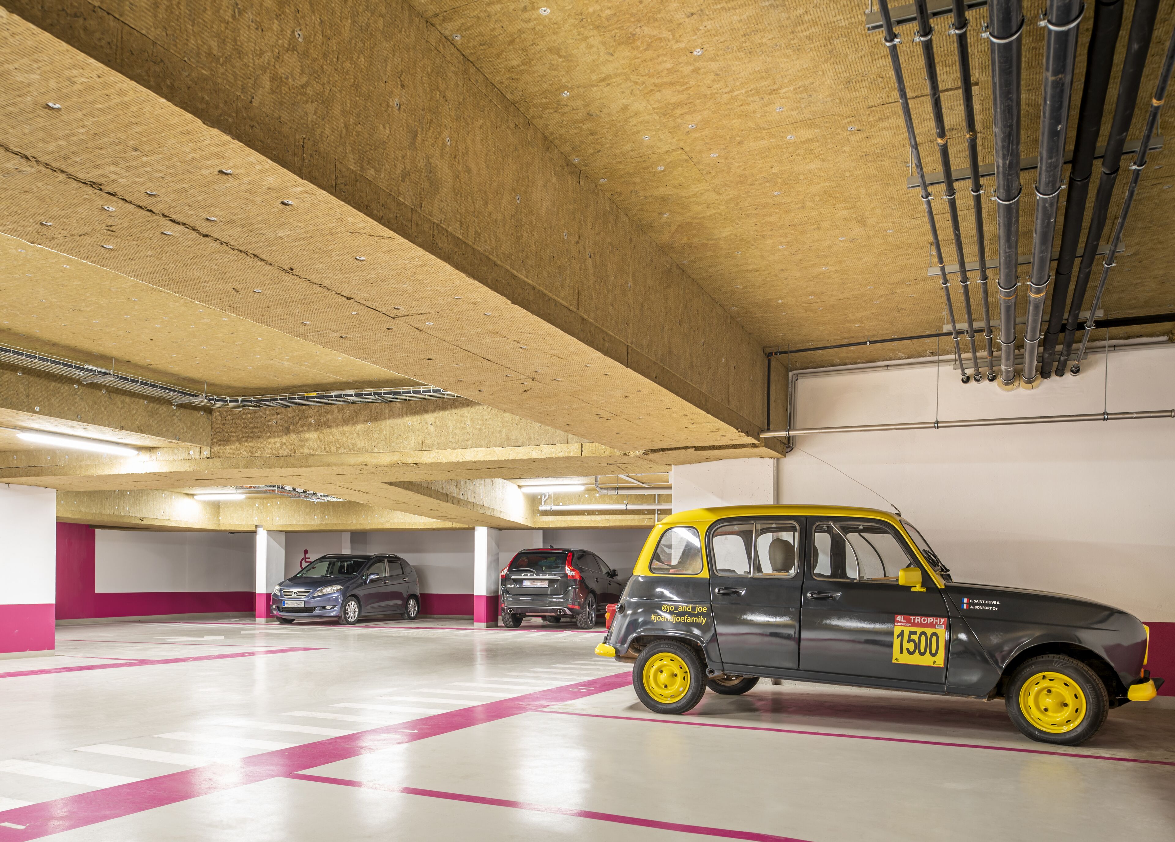 Un aparcamiento con un coche amarillo estacionado en un lugar reservado.