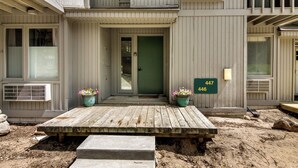 A two-story building with a wooden deck, a green door, and a mailbox with numbers 447 and 446. - Sanctuary at Sundendorf- New Updates! (Bellaire)