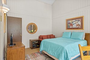 A bedroom with a bed, a desk, a mirror, a bookshelf, and a framed picture on the wall.