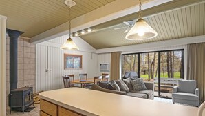 A spacious living area with a large window, a fireplace, and a dining table. - Sanctuary at Sundendorf- New Updates! (Bellaire)
