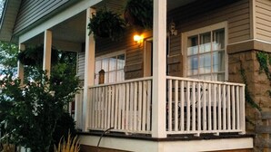 A house with a covered porch, a stone foundation, and a hanging planter.