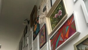 A staircase with a handrail, leading up to a wall adorned with various framed artworks.