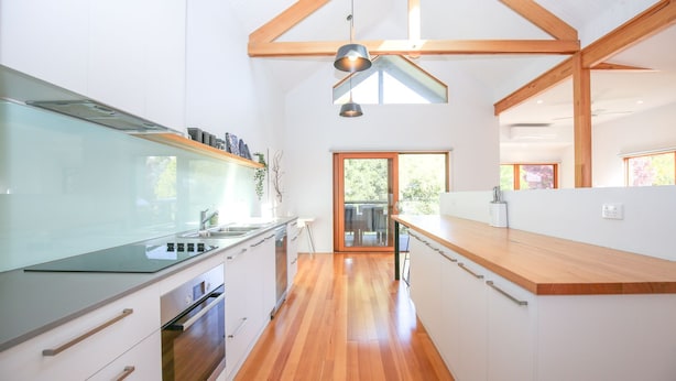Une cuisine moderne avec des meubles blancs, un plan de travail en bois et un four encastré.
