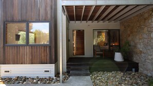 Une maison moderne avec une façade en bois, un mur en pierre et un escalier en pierre menant à un porche.
